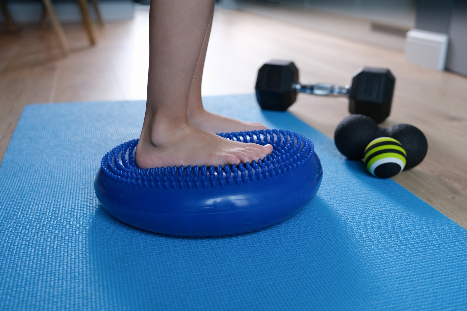 Child foot is resting on blue massage balancing cushion. Balance exercises on balance cushion concept